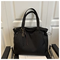 Detail of a large black nylon tote bag featuring a tennis racket charm and drawstring sides - With Charm / Black