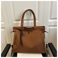 Close-up of brown nylon tote bag with tennis racket charm and tassel on a chair - With Charm / Brown