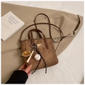 Detail der dunkelbraunen matten Beuteltasche mit goldenem Logo und Baseball-Anhänger - Mit Anhänger / Braun