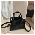 Macro detail of black woven PU leather texture and gold metal zipper on small square bag - Black