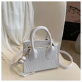 Close-up of white crossbody bag with woven texture, round handles and gold hardware - White