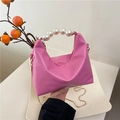 Bolso de media luna rosa con asa de perlas y cadena dorada sostenido con la mano - rosa intenso