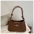 Detail of a brown woven shoulder bag featuring a silver star logo and knotted rope handle - Tan