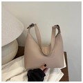Detail of a beige leather hobo bag with adjustable strap on a wooden table setup - Khaki