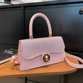 Pink crossbody square bag with shimmering rhinestones and gold twist lock on wooden table - Pink