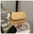Detail of khaki saddle bag featuring geometric embossed texture and gold hardware logo - Khaki