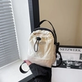 Minimalist beige nylon drawstring bucket bag with black strap in a lifestyle scene - White