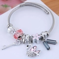 Close-up of adjustable stainless steel bangle with swan charm and crystal beads - Pink