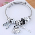 Macro shot of silver bangle with crystal beads and swan charm showing fine textures - Black