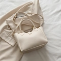 Bolso tote beige de cuero con patrón lichi y correa ajustable sobre fondo de traje - Estilo básico / Blanco Roto