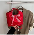 Detalle de bolso rojo de cuero PU con lazo de encaje blanco sobre una chaqueta marrón - Rojo