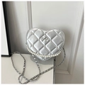 Detail of silver heart-shaped quilted crossbody bag with pearl trim and bow accent - Silver