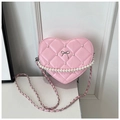 Detailed view of pink heart-shaped quilted bag with pearls and silver bow charm - Pink
