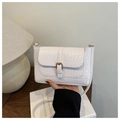 Detalle de bolso bandolera blanco trenzado con hebilla dorada sobre fondo con textura - Blanco