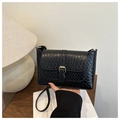 Close-up of black woven pattern texture and gold metal buckle on a small square crossbody bag - Embossed/Woven Texture / Black