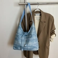 Blue denim tote bag with white texture and bow detail hanging on a hanger - Blue