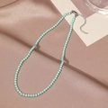 Détail du collier de perles vert menthe avec fermoir mousqueton argenté sur du satin - Style Petite Perle (X3094) / Vert Pâle