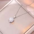 Macro shot of a silver flower necklace featuring sparkling cubic zirconia on a gift box - Silver Flower Rotating Necklace