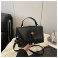 Detalle de bolso negro en contraste con herrajes dorados y motivos geométricos vintage - Negro