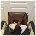 Gros plan d'un sac besace marron foncé en cuir lisse avec un design rétro moderne à l'épaule - Marron