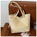 Detail einer beigen Canvas-Tragetasche mit Druckknopftasche und TAIMEIBAG-Logo auf Leder - Khaki