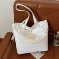 Versatile off-white canvas tote bag with large capacity and logo on a leather sofa - Off White