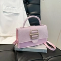 Pink patchwork handbag with sequined flap and gold buckle on a stylish book setting - Pink