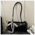 Detail of glossy black faux leather shoulder bag featuring a white lace bow decoration - Black