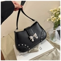 Detail of a black leather saddle bag with silver bow buckle and rivet accents - Black