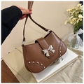 Detail of brown faux leather saddle bag with silver bow buckle and rivet accents - Brown
