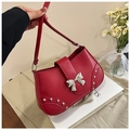 Detail of red underarm bag featuring silver metal bow and studded rivets decoration - Red