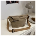 Khaki nylon crossbody bag with adjustable strap and front pocket on a white desk - Khaki