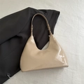 Detail view of glossy beige patent leather underarm bag on a textured background - Patent Surface / Khaki (9287)