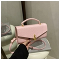 Detalle del bolso rosa de cuero trenzado con hebilla metálica de nota musical en color dorado - Rosa