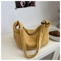 Close-up of a yellow corduroy hobo bag with an adjustable strap on a white table - Yellow