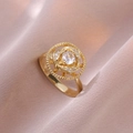 Détail macro bague dorée fleurie avec cristal sur fond de soie rose élégant - Bague Fleur Rotative Dorée (J0342)