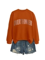 Detail of OVERTHINKER orange crewneck sweatshirt paired with distressed denim shorts - Burnt Orange