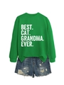 Dettaglio della felpa verde con stampa Best Cat Grandma Ever e pantaloncini in denim - S / Verde Erba (Stampa Bianca)