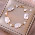 Detalle de pulsera de perlas barrocas con cuentas doradas sobre seda color champán - Pulsera / Blanco