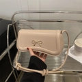 Beige faux leather crossbody bag with a gold metal bow charm and adjustable strap - Khaki