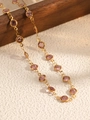 Macro detail of gold-tone chain necklace with bezel-set purple round faceted gemstones - Gold + Purple