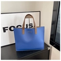 Detalle de bolso tote de piel azul granulada con letras doradas y asas marrones - Azul