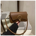 Close-up of caramel rectangle shoulder bag featuring a prominent gold round metal buckle - Brown