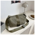 Detail view of army green nylon crossbody bag on a desk with lifestyle props - Green