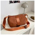 Orange-brown nylon crossbody bag with buckle detail on a modern minimalist tabletop - Orange