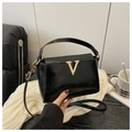 Detail of elegant black glossy patent leather handbag with golden V-shaped buckle - Black