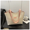 Close-up of beige woven tote bag with pink leather straps and fashion label detailing - Pink