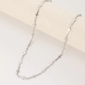 Minimalistische zilveren kruisketting op een beige cilindrisch display - Goud