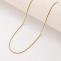 Detail einer dünnen goldenen Schlangenkette, gewickelt um einen weißen Zylinder - Rundschlangenglied(STN25295-GO-1.9mm) / 1.9mm