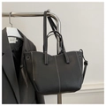 Dettaglio borsa tote in pelle nera con cuciture bianche a contrasto su supporto metallico - Nero
